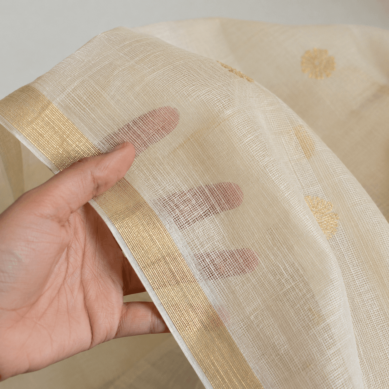 The fabric held in hand, showing its sheer texture